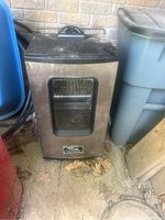 Full front view of the black Masterbuilt electric smoker showing glass door and handle.