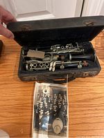 Opened clarinet case revealing a vintage clarinet inside along with the old photograph placed below.