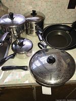 Complete set of T-Fal stainless steel pots and pans with lids shown on countertop