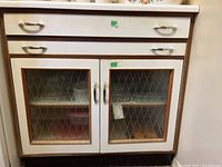 Front view of the retro kitchen cabinet showing the drawer on top and glass paneled double doors below with diamond pattern textured glass.