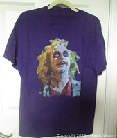 Full view of the purple Beetlejuice t-shirt hanging, showing the front graphic and overall condition.