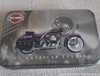 Front view of metallic collector tin with Harley-Davidson motorcycle image, logo and 'AN AMERICAN LEGEND' text