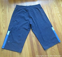 Back view of navy blue wide leg Lululemon capri pants showing the waistband, leg length, and bottom stripe patches with logo on left leg.