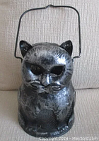 Front view of vintage cat-shaped lantern with detailed rustic metal finish and handle.