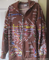 Front view of brown zip-up hoodie printed with detailed NYC subway map featuring multiple colored subway routes and station names.