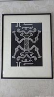 Full view of framed lino cut block print art with abstract symmetrical design in black and white.