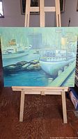 Front view of the oil painting on easel showing multiple docked boats and marina scene.