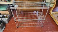 Front view of three-tier metal wire shelving unit showing wire shelves and chrome finish.