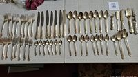 Full layout of all 54 pieces showing various forks, knives, spoons, and serving utensils arranged on table.
