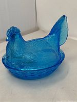 Side view of the aqua blue glass hen on nest showing detailed feathers and basket weave pattern.