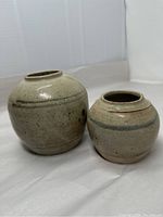 Two Chinese Ming Dynasty glazed stoneware jars side by side, showing color, shape and size difference.