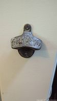 Front view of 7up vintage wall-mounted bottle opener made of metal with raised text