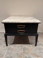 Front view of end table showing marble top, two drawers and tapered legs