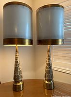 Pair of conical ceramic table lamps with abstract gold patterns and matching shades on wooden surface