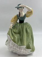 Front view of the Royal Doulton Buttercup figurine depicting a woman in a green dress with yellow sleeves and green hat.