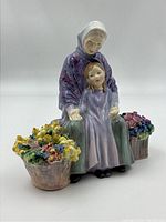 Full front view of the figurine showing grandmother, child, and flower baskets