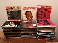 Wide view showing stacks of vintage vinyl records with visible covers: 'Satch Plays Fats,' 'Satchmo The Great,' and 'Mills Brothers' albums.