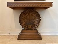 Front view of walnut console table showing carved shell pedestal and apron detail