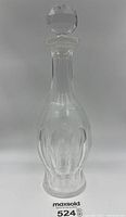 Full view of clear Waterford crystal decanter showing thumbprint pattern along the lower half, tall slim neck, and faceted stopper on top.