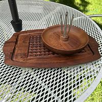 Carving board with nut bowl and metal nut picks displayed on outdoor table.