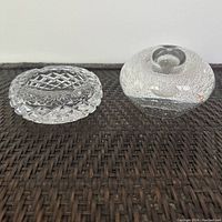 Side view of ashtray and art glass bud vase placed on woven surface