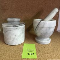 Front view of marble butter keeper with lid and marble mortar and pestle.