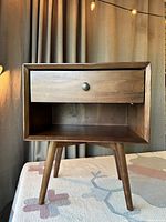 Front view of the MCM style wooden side table showing the drawer and open shelf.