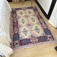Area rug showing full length beside furniture for scale. Pastel colors and pattern visible.