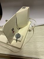 Left side view of the white SEB electric meat slicer showing the circular blade, adjustable thickness dial, and base.