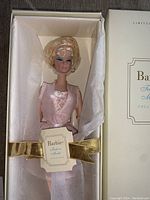 Doll in pale pink lingerie ensemble inside Fashion Model Collection box with gold ribbon and Barbie tag
