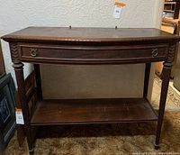 Full front view of antique wood console table showing single long drawer, carved detailing, and open bottom shelf.