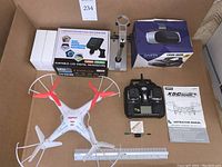 Overview of drone, microscope, VR headset boxes and items inside, including controller and instruction manual for drone.