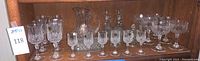 Wide shot of entire set including glasses, pitcher, and dishes on wooden shelf