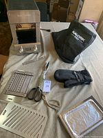 Full lot overview showing electric grill, cover, grilling racks, tongs, and oven mitts on a fabric-covered table.