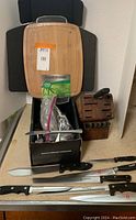 Photo of butcher block, cutting knives, bamboo cutting board, and box containing silverware.