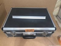 Closed hard aluminum carrying case on cardboard