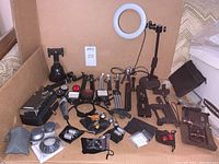 Wide view of all phone photography accessories arranged in a box: tripods, LED lights, rings lights, lenses, mounts, digital microscope camera, and more.