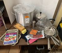 Overview of entire lot showing pots, pans, holders, chef basket, broiler sets, and measuring graduate.