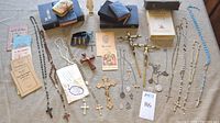 Overview photo of lot items showing rosaries, medals, crucifixes, and books arranged on table