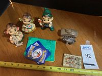 Full lot shown together with measuring tape for scale, includes figurines, plastic tank, bear, paperweight, Pokemon cards, and pouch.