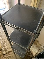 Close up showing the black shelf mats dust and chrome tubular frame of shelving.