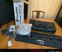 Full lot contents on wooden table showing trunk nets, cooler, organizer, floor mats, and KUST sunshade box