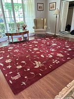 Full view of the red floral area rug placed on hardwood floor with furniture around.