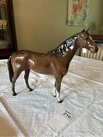 Image showing left side profile of the glossy Beswick chestnut brown horse figurine mare on a white patterned tablecloth.