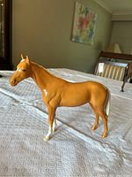 Side view of the palomino horse figurine showing its glossy golden tan body and white markings on legs and tail.