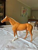 Side view of large Palomino Beswick horse figurine showing details of body and stance on table.