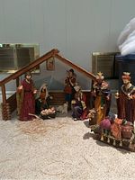 Full view of the wooden stable with nativity figures including Wise Men, shepherd, and camel with gifts.