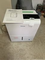 Full front view of the white Living 30-pint dehumidifier with instruction manual placed on top.