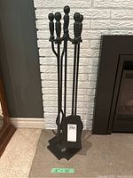 Front view of the fireplace utensils set on stand showing all four tools with round handles and the stand