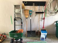Photo showing 6 ft aluminum step ladder, broom, squeegee, shovel, salt container, dustpan, and hose coiled on wall.